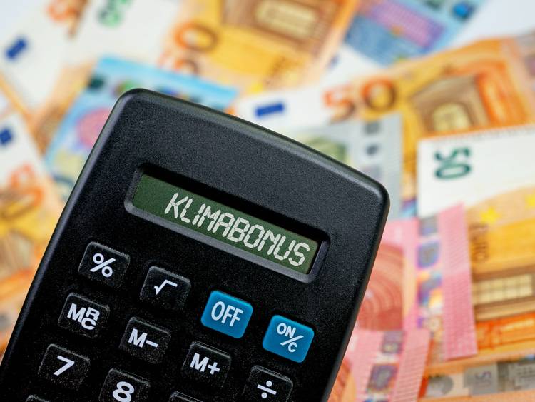 Taschenrechner mit der Anzeige „Klimabonus“ auf einem von Euro-Banknoten umgebenen Bildschirm.