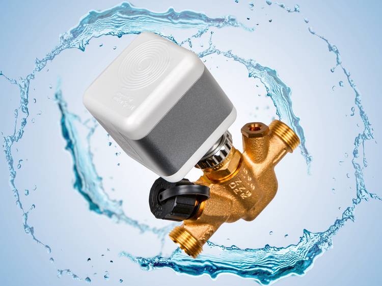 Alt-Text: „Digitale Wasserregelarmatur mit goldfarbenem Gehäuse und grauem Oberteil, umgeben von spritzendem Wasser auf hellblauem Hintergrund, symbolisiert innovative Steuerungstechnologie für die Optimierung von Energieeffizienz in modernen Gebäudetechniksystemen.