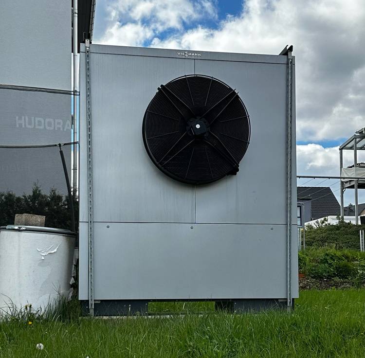 ALT-Text: „Großer industrieller Ventilator auf einer Außeneinheit in einem Gewerbegebäudekomplex, ideal für effektive Klimatisierung und Energieeffizienz in der Gebäudetechnik.