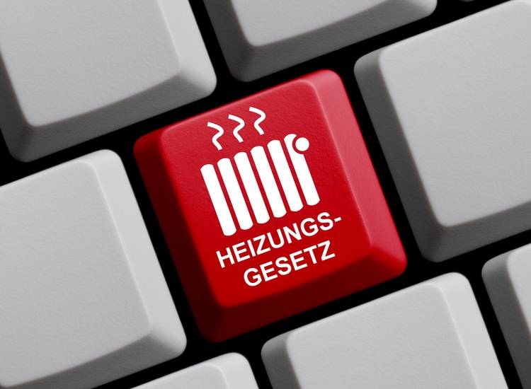 Alt-Text: „Nahaufnahme einer Tastatur mit hervorgehobener roter Taste, beschriftet mit ‚Heizungsgesetz‘, daneben ein Symbol eines Heizkörpers mit Wärmewellen zur Darstellung neuer Gesetzgebungen in der Heiztechnikbranche.