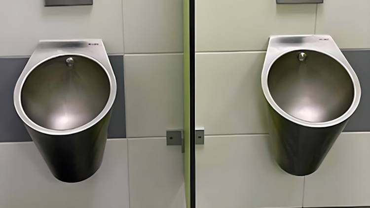 Zwei wandhängende Edelstahl-Urinale in einem Sanitärraum mit hell gefliesten Wänden, ideal für gewerbliche Gebäude zur Verbesserung der Hygienestandards und Wartungsfreundlichkeit.